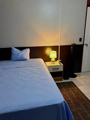 a bedroom with a bed and a lamp on a night stand at Casa Armon - Frente a Estadio Cuscatlán in San Salvador