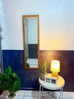 a table with a lamp and a mirror on a wall at Casa Armon - Frente a Estadio Cuscatlán in San Salvador