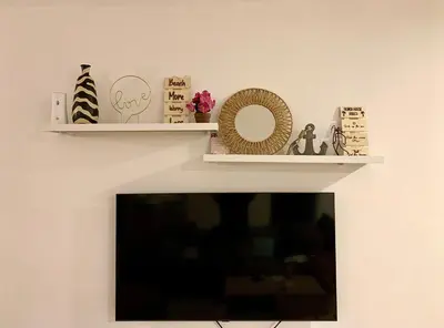 two white shelves on a wall with a tv at Makai Beach Apartment in El Zapote
