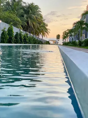a swimming pool with palm trees on the side of a building at Makai Beach Apartment in El Zapote