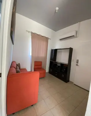 a living room with an orange couch and a flat screen tv at Casa acogedora con piscina y seguridad las 24 horas in Ahuachapán