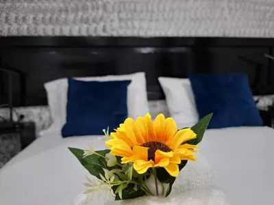 a yellow flower sitting on a bed with blue pillows at The Bello Lodging in Sonsonate