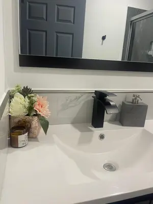 a bathroom sink with a mirror and flowers on it at The Bello Lodging in Sonsonate