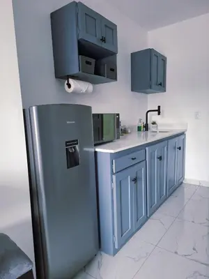 a kitchen with blue cabinets and a stainless steel refrigerator at The Bello Lodging in Sonsonate