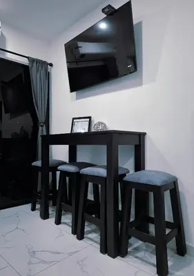 a black table and stools with a television on a wall at The Bello Lodging in Sonsonate