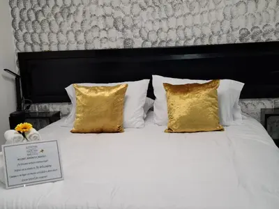 a white bed with gold pillows and a sign on it at The Bello Lodging in Sonsonate
