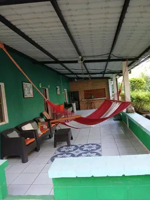 a hammock on a patio with a green wall at Casa de playa en lomas de san blas in Playa San Blas