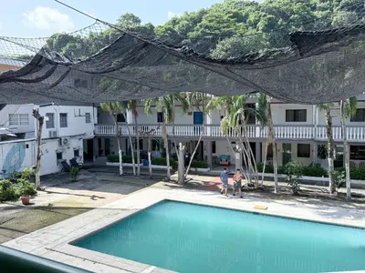 two people standing by a swimming pool in front of a house at Cozy Loft with pool and beach in Surf City in La Libertad