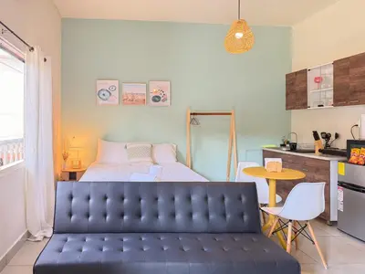 a bedroom with a bed and a black leather couch at Cozy Loft with pool and beach in Surf City in La Libertad