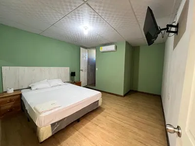 a bedroom with a bed in a room with green walls at Hostal Noche de Luna in San Salvador