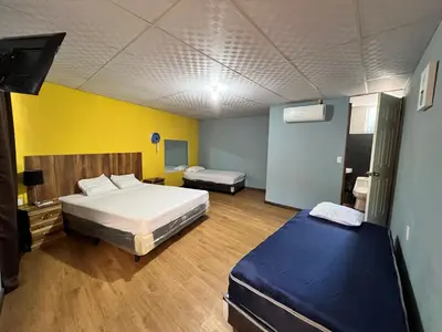 a bedroom with two beds and a yellow wall at Hostal Noche de Luna in San Salvador
