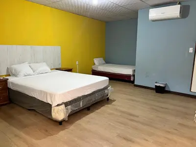 a bedroom with two beds and a yellow wall at Hostal Noche de Luna in San Salvador