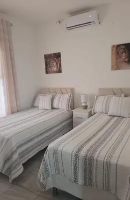 two beds in a room with white walls at Casa Luna Villa Verde State in Santa Ana