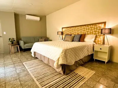 a bedroom with a large bed and a couch at Casa Maruca- 2 bedrooms Home for 5 Guests - A charming getaway near downtown & financial hub area! in San Salvador