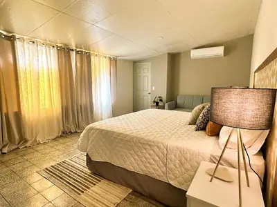 a bedroom with a bed with a lamp and a couch at Casa Maruca- 2 bedrooms Home for 5 Guests - A charming getaway near downtown & financial hub area! in San Salvador