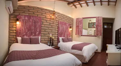 a bedroom with two beds and a brick wall at Casa 1800 Suchitoto Boutique in Suchitoto