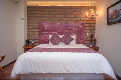 a bedroom with a large bed with a brick wall at Casa 1800 Suchitoto Boutique in Suchitoto