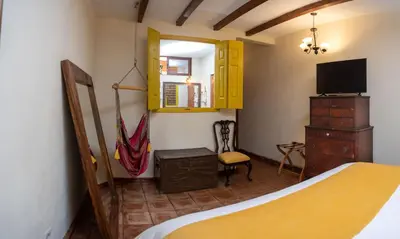 a bedroom with a bed and a dresser and a tv at Casa 1800 Suchitoto Boutique in Suchitoto