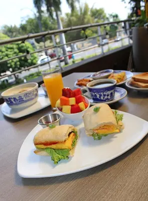 a table with a sandwich and fruit and a glass of orange juice at Terra Bella Hotel Boutique in San Salvador