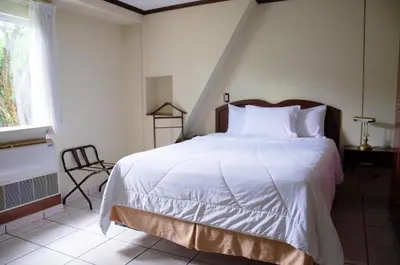 a bedroom with a bed with white sheets and a window at Hotel Gardenia Inn in San Salvador