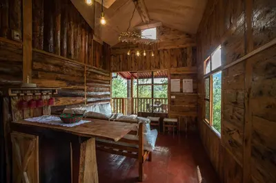 a wooden cabin with a table and a couch at Villa Verde in Perquín