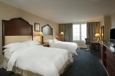 a hotel room with three beds and a television at Barceló San Salvador in San Salvador