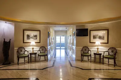 a lobby with chairs and tables and a television at Barceló San Salvador in San Salvador