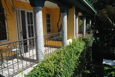 a yellow house with columns on a porch at Apart Hotel Valle Verde PLANES DE RENDEROS in San Salvador