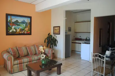 a living room with a couch and a table and a kitchen at Apart Hotel Valle Verde PLANES DE RENDEROS in San Salvador