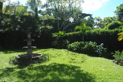 a garden with a bird bath in the grass at Apart Hotel Valle Verde PLANES DE RENDEROS in San Salvador