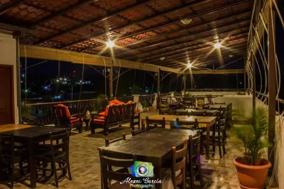 a restaurant with tables and chairs on a balcony at night at Hotel & Restaurant Fleur de Lis in Concepción de Ataco