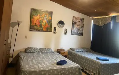 a bedroom with two beds and a painting on the wall at Hostal Cumbres de El Salvador in San Salvador