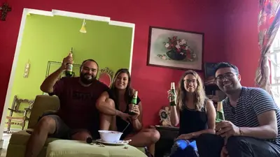 a group of people sitting in a living room holding beer bottles at Hostal Cumbres del Volcan Flor Blanca in San Salvador