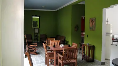 a dining room with green walls and a table and chairs at Hostal Cumbres del Volcan Flor Blanca in San Salvador