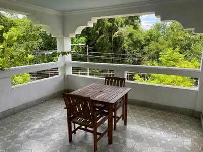 a wooden table and two chairs on a porch with two windows at Hostal Cumbres del Volcan Flor Blanca in San Salvador