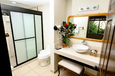 a bathroom with a sink and a toilet and a mirror at Paraiso Escondido Hotel Villas & Resort in El Níspero