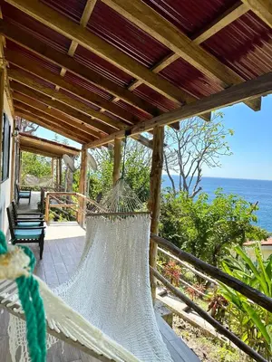 a hammock on a porch overlooking the ocean at Paraiso Escondido Hotel Villas & Resort in El Níspero