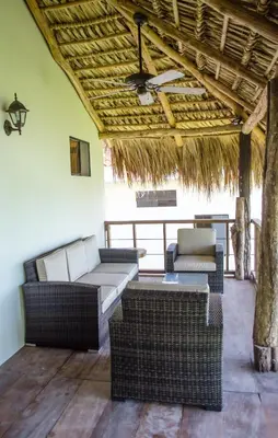 a patio with wicker furniture and a straw roof at Paraiso Escondido Hotel Villas & Resort in El Níspero