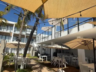 a building with tables and umbrellas in front of it at Coco Blue a New Beach Resort in La Libertad