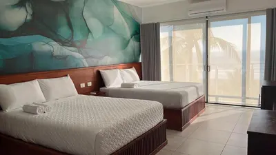 a hotel room with two beds and a large window at Coco Blue a New Beach Resort in La Libertad