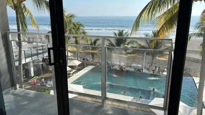 a view of a swimming pool and the beach from a hotel room at Coco Blue a New Beach Resort in La Libertad