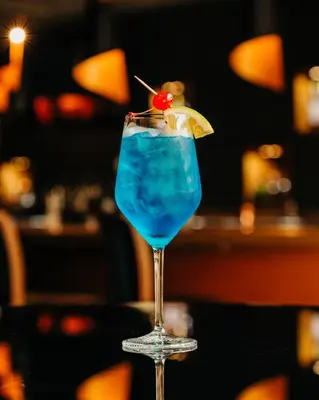a blue drink in a glass with a cherry on it at Plaza Hotel and Suites in San Salvador