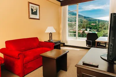 a living room with a red chair and a window at Plaza Hotel and Suites in San Salvador