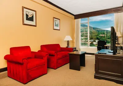 a living room with two red chairs and a television at Plaza Hotel and Suites in San Salvador