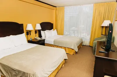 a hotel room with two beds and a flat screen tv at Plaza Hotel and Suites in San Salvador