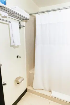 a bathroom with a shower with a white shower curtain at Plaza Hotel and Suites in San Salvador