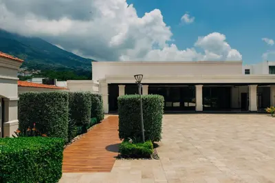 a large building with bushes in front of it at Plaza Hotel and Suites in San Salvador