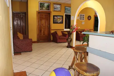 a living room with yellow walls and a counter and stools at Hotel Pasadena II in San Salvador