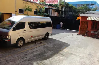 a white van parked in a parking lot next to a building at Hotel Pasadena II in San Salvador