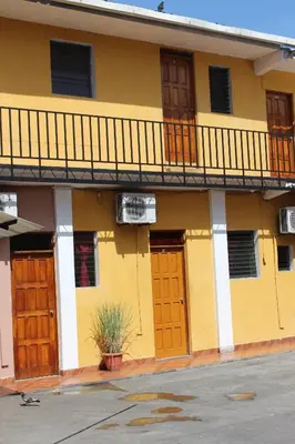 a yellow building with wooden doors and a balcony at Hotel Pasadena II in San Salvador